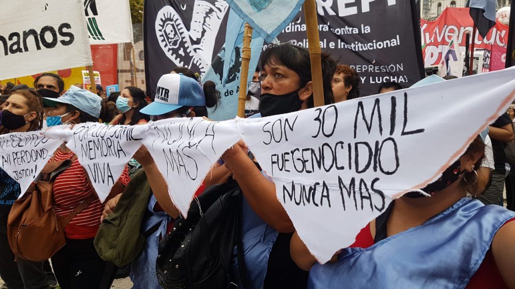 Personas con pañuelos de "Nunca Más" y "Son 30 mil. Fue genocidio".